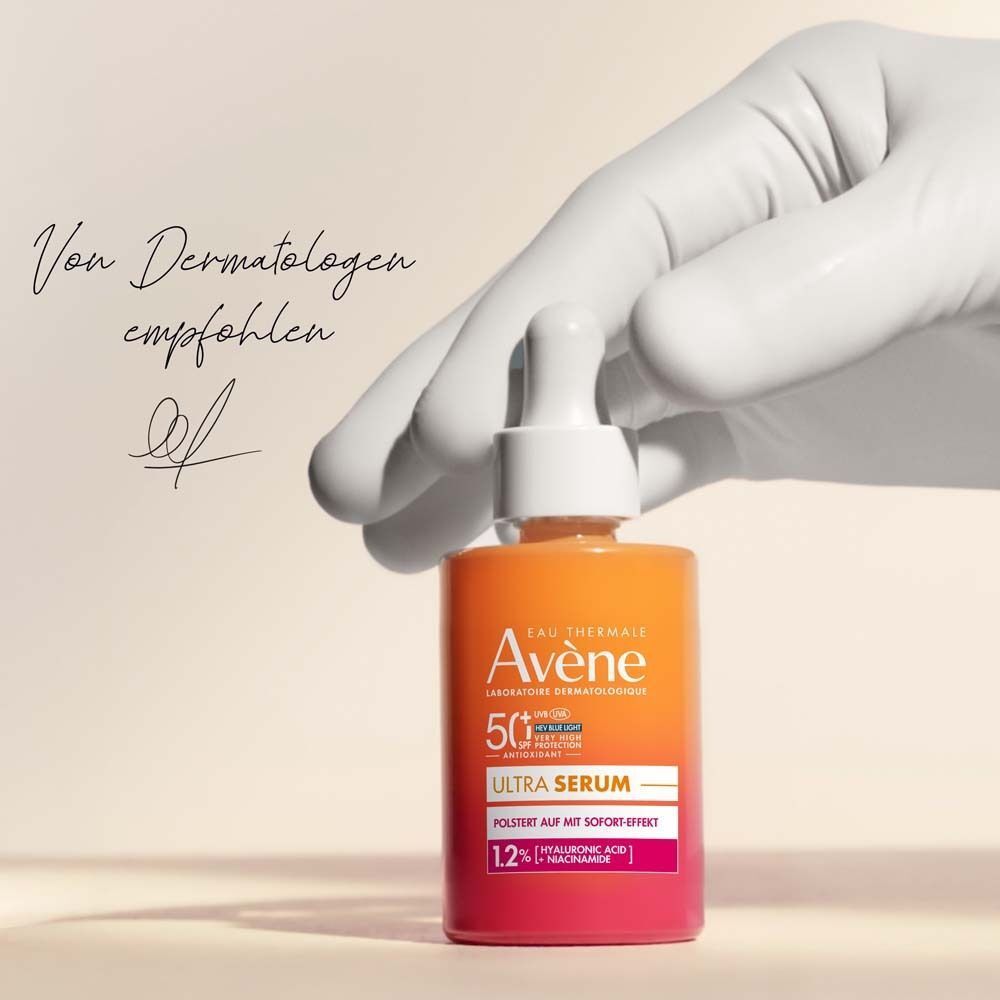 Hand mit AVENE Ultra Serum SPF 50+. Orange-rosa Flasche, Text: Ultra Serum, 50+. Unterschrift.