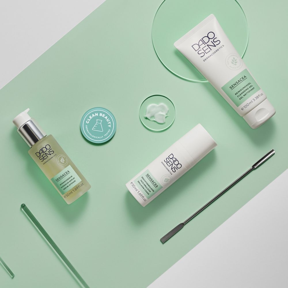DADO SENS SENSACEA Produkte: Serum, Reinigungsgel, Emulsion und ein Spatel auf mintgrünem Hintergrund.