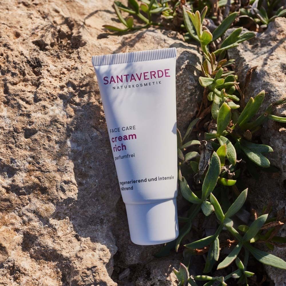 Weiße Creme-Tube mit lila Schrift auf Stein. Aufschrift: SANTAVERDE, FACE CARE, cream rich ohne Duft. Regenerierend und intensiv nährend.