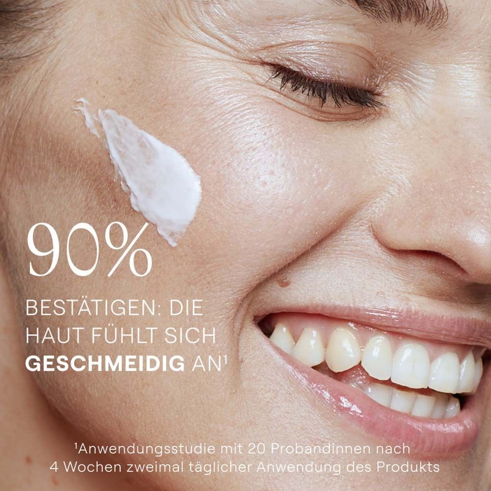 Nahaufnahme eines lächelnden Gesichts mit Creme auf der Haut. Text: 90% bestätigen: Die Haut fühlt sich geschmeidig an.