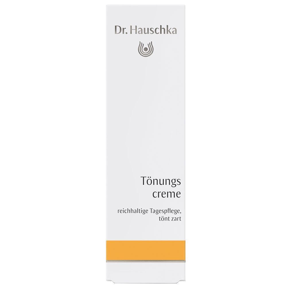 Weiße Verpackung Dr. Hauschka Getönte Creme mit orangefarbenem Band.