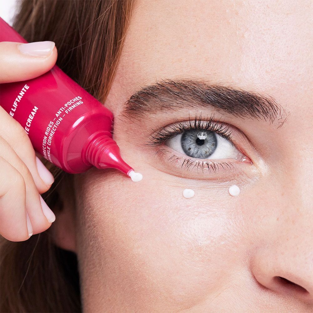 Nahaufnahme eines Auges. Eine Tube gibt Creme ab. Text auf der Tube: Lift Eye Cream, Correction Rides - Anti-Poches.