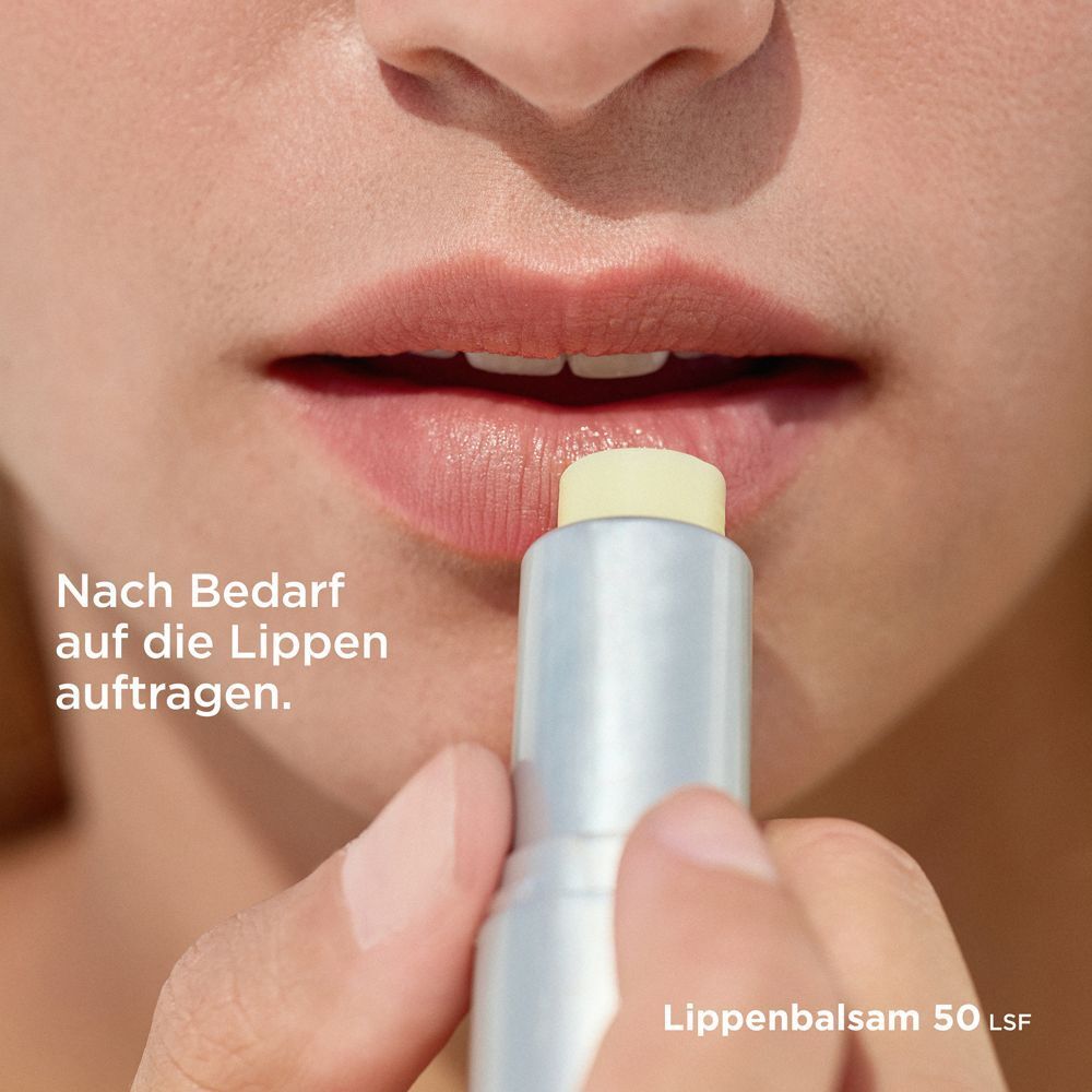 Lippen werden mit einem Lippenbalsam-Stift eingerieben. Der Stift hat eine weiß-silberne Hülle mit orangefarbener Schrift.