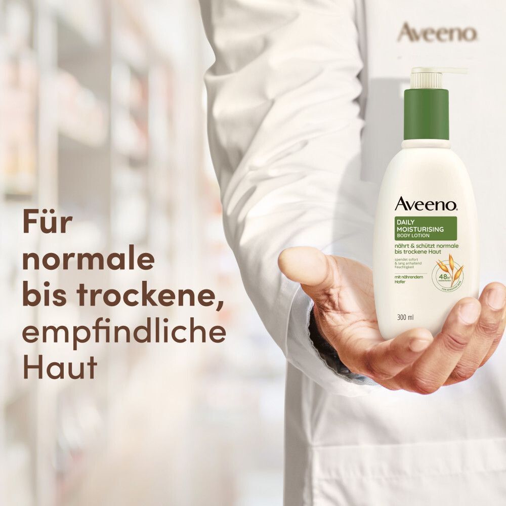Arzt hält AVEENO Daily Moisturising Bodylotion Flasche. Text: Für normale bis trockene, empfindliche Haut. 300ml.