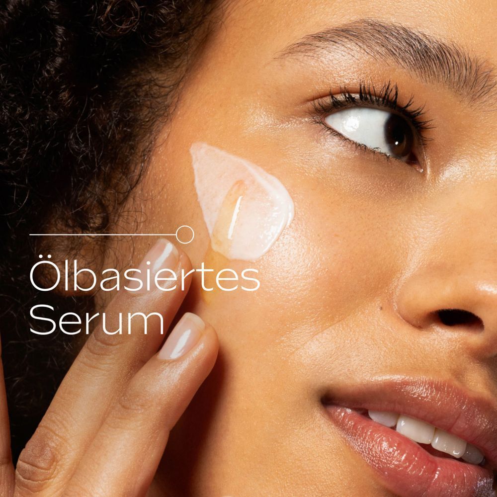 Nahaufnahme einer Frau, die Serum auf ihre Haut aufträgt. Text: Ölbasiertes Serum.