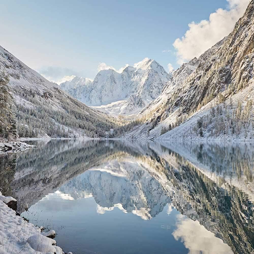 Landschaft mit Bergen und See. Schnee bedeckt die Berge. Spiegelung im Wasser.