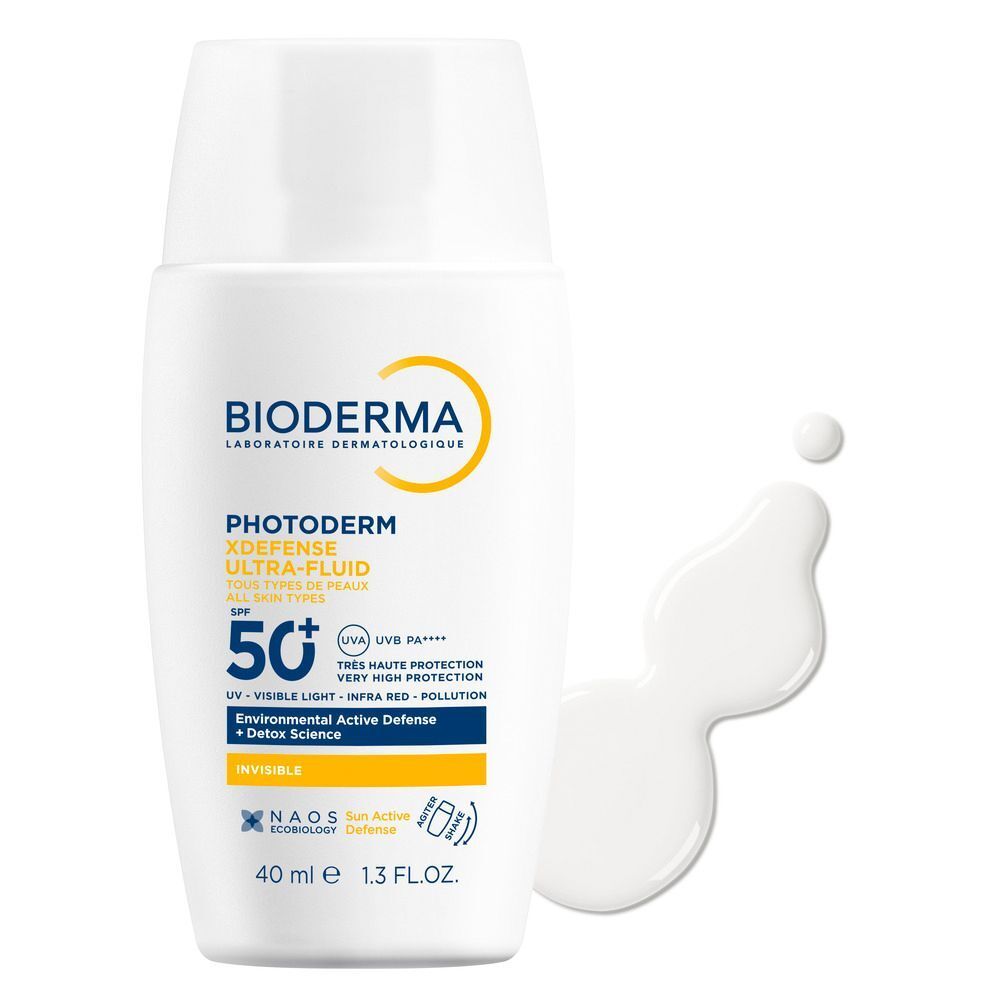 Weiße Flasche mit weißem Fluid daneben. Aufschrift: BIODERMA Photoderm Xdefense Ultra-Fluid LSF 50+.