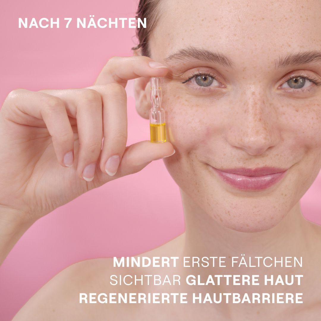 Nahaufnahme einer Frau, die eine Ampulle hält. Text: Mindert erste Fältchen, sichtbar glattere Haut, regenerierte Hautbarriere. Rosa Hintergrund.
