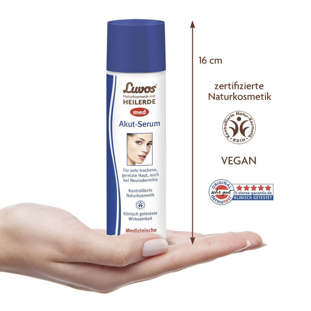 LUVOS Akut-Serum in Hand. Flasche mit blauem Deckel, weißem Etikett. 16 cm hoch. Vegan-Siegel und Zertifizierung.