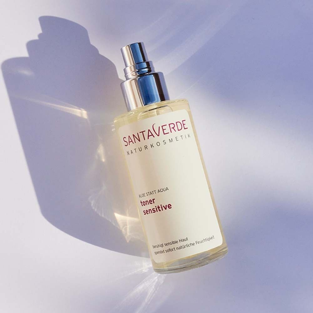 Eine Sprühflasche mit silbernem Verschluss. Aufschrift: SANTAVERDE, toner sensitive. Auf hellem Hintergrund mit Schatten.