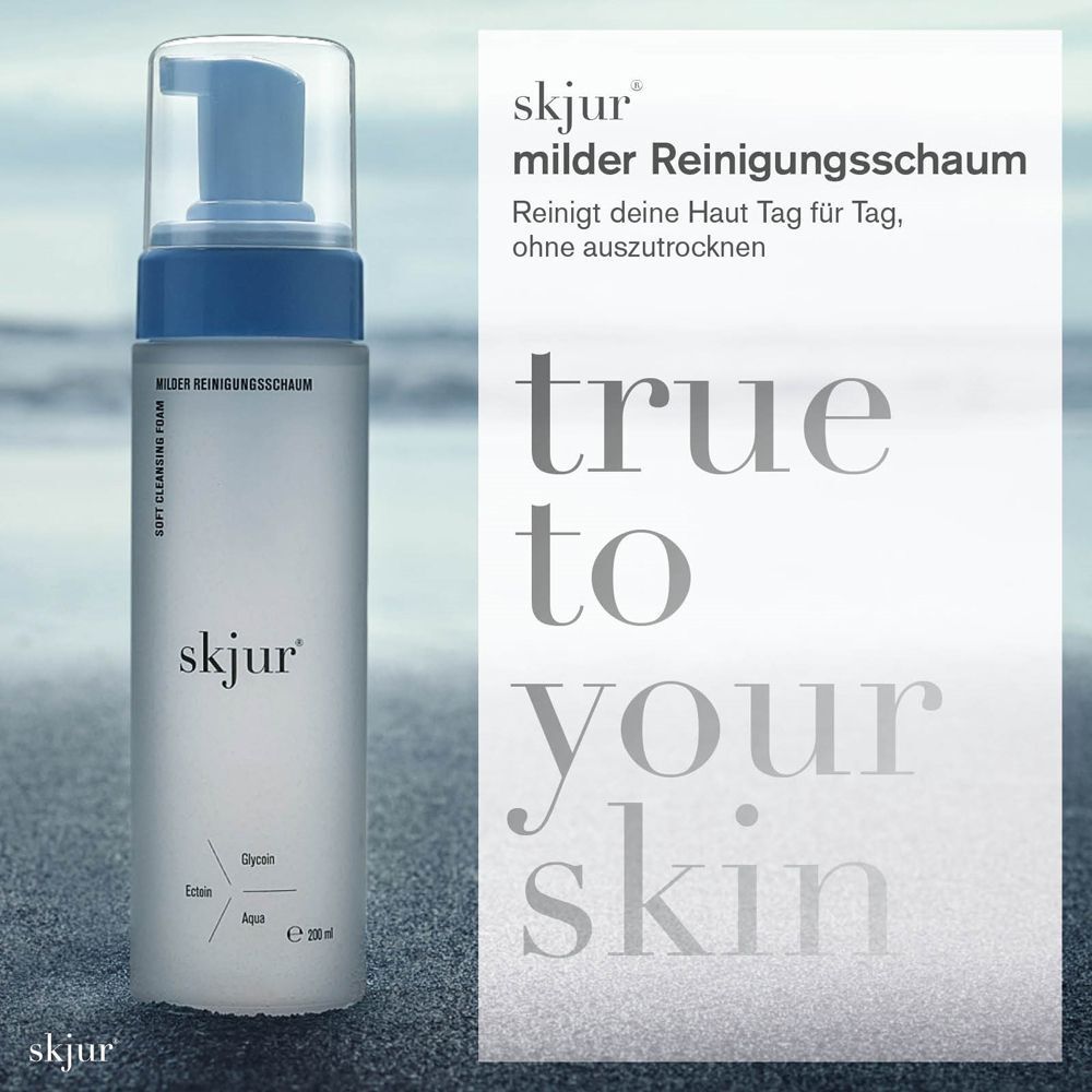 Eine Flasche Reinigungsschaum mit blauem Pumpkopf. Aufschrift: skjur, milder Reinigungsschaum, e 200 ml. Hintergrund: Strand und Meer.