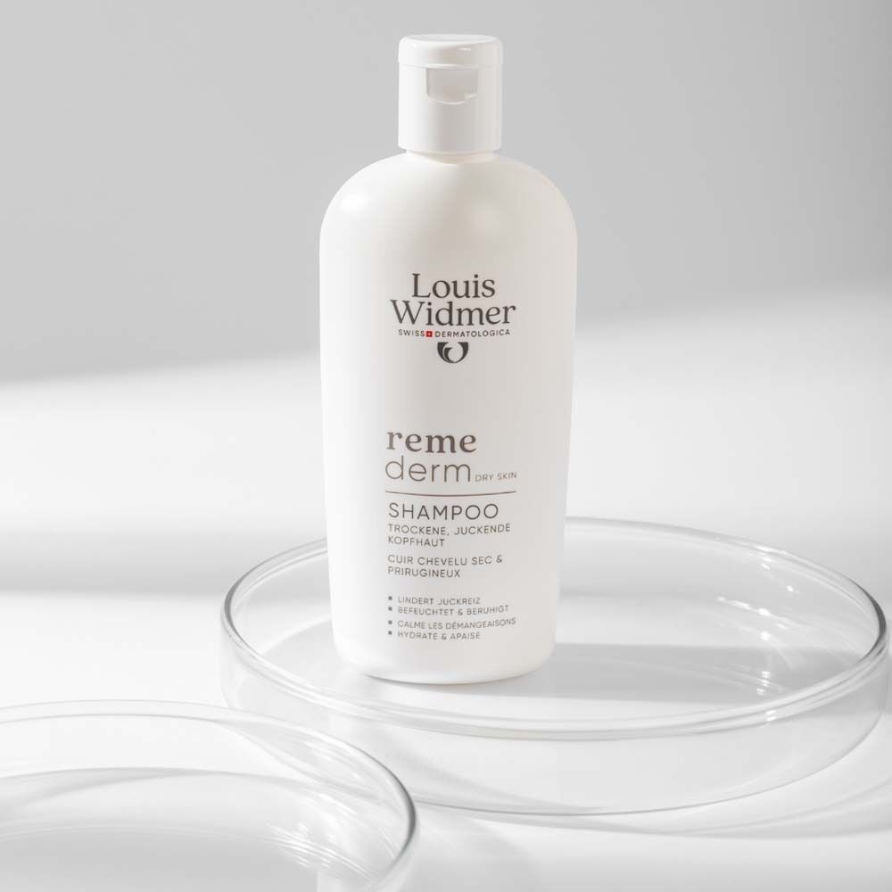Weiße Shampoo-Flasche auf Glasplatte. Aufschrift: Louis Widmer, remederm dry skin, Shampoo, für trockene, juckende Kopfhaut.