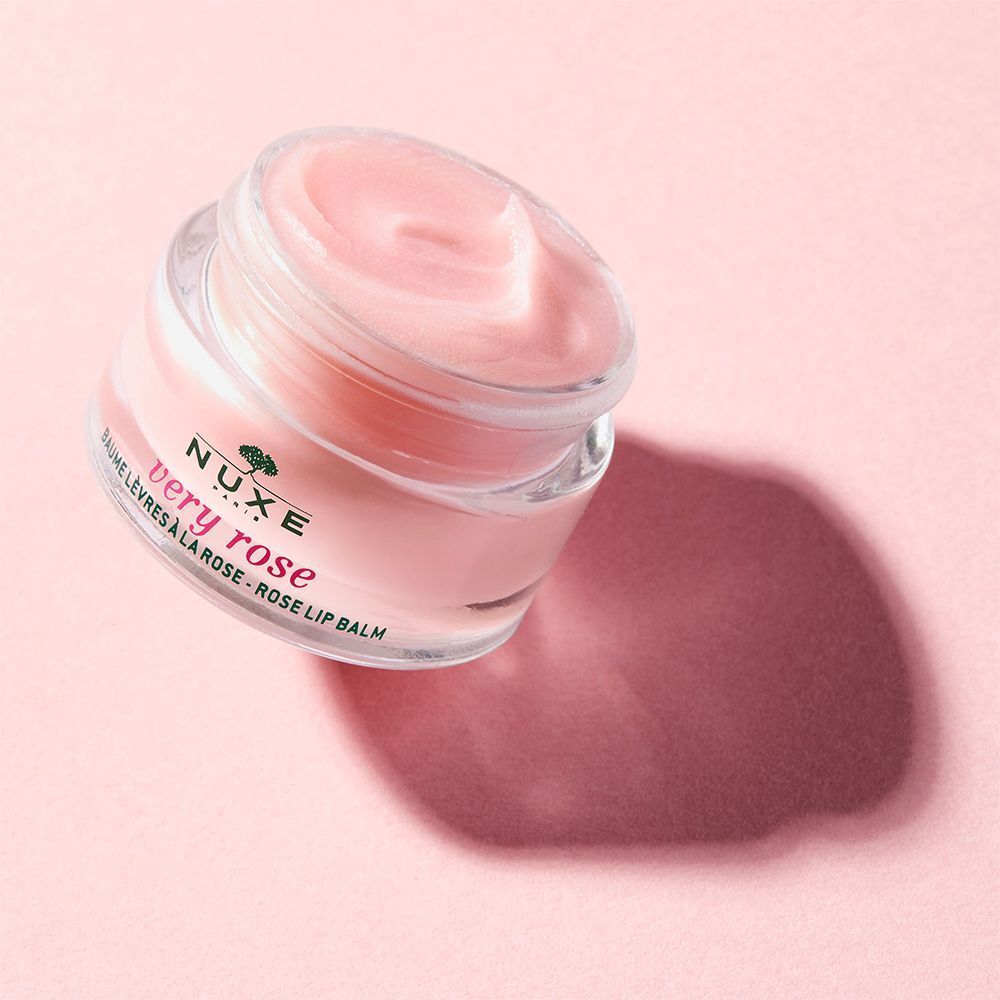 Ein offener, rosa Lippenbalsam-Tiegel auf rosa Untergrund. Aufschrift: NUXE Very Rose. Text: Baume Lèvres à la Rose.