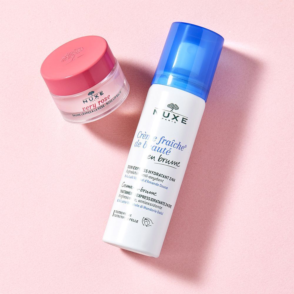 Ein Lippenbalsam-Tiegel und eine Sprühflasche auf rosa Untergrund. Aufschrift: NUXE. Text: Crème fraîche de beauté.