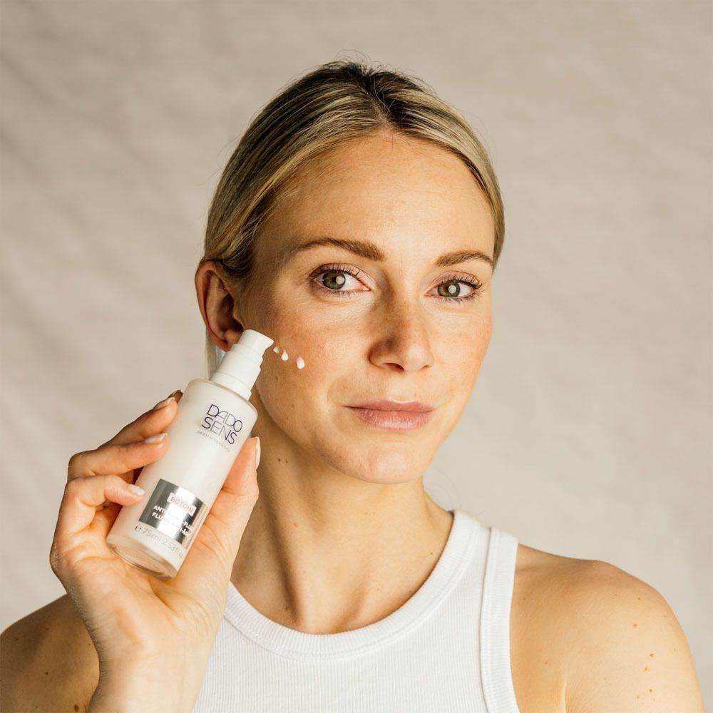 Frau trägt DADO SENS ECOTIN Anti-Aging-Fluid auf die Wange auf.