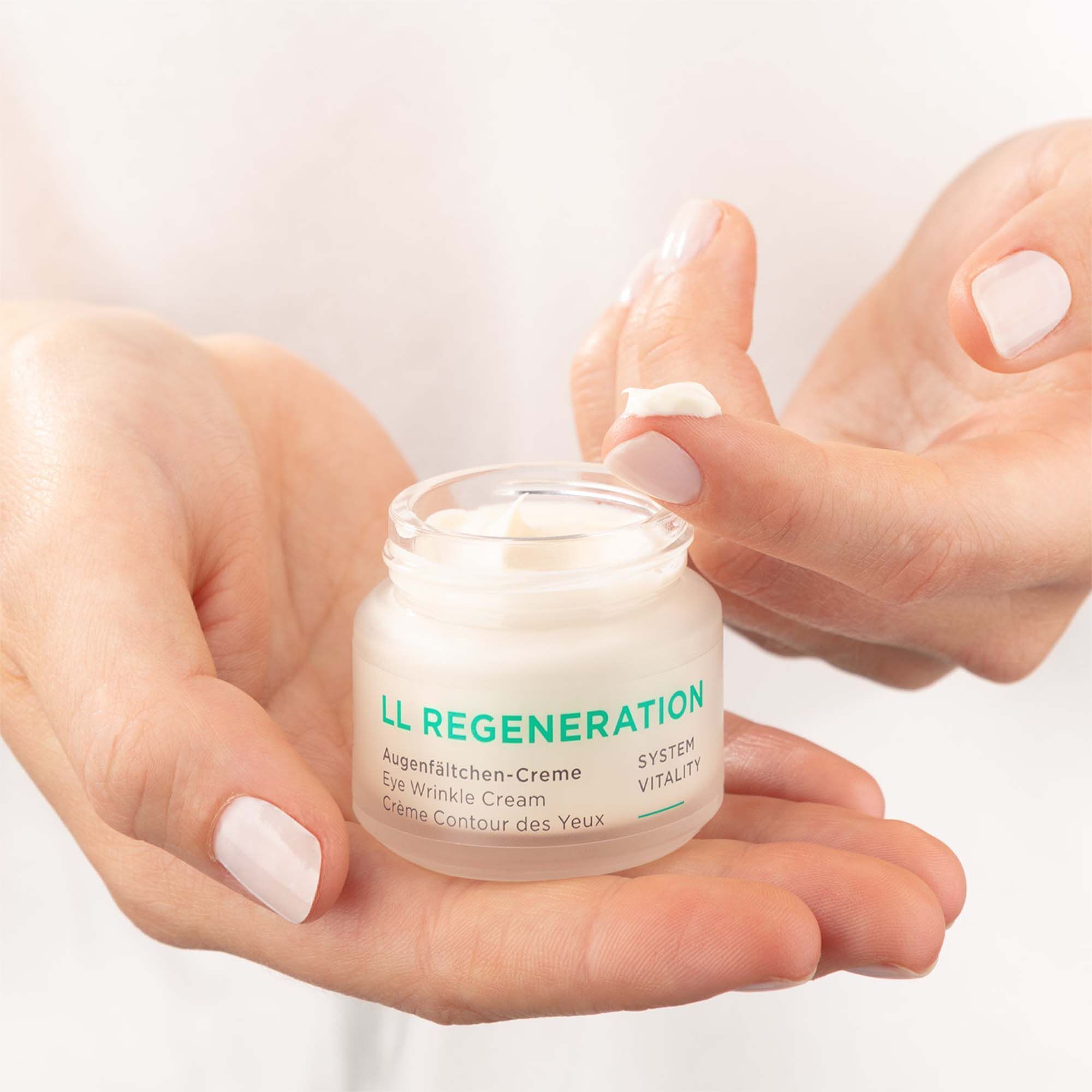 Hände halten einen Tiegel LL Regeneration Augen-Creme.