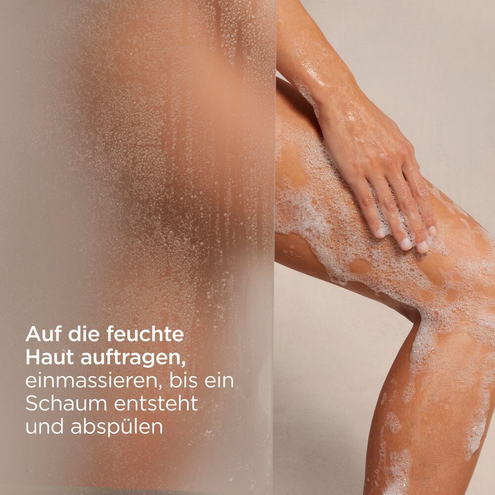 Person unter der Dusche. Text: Auf die feuchte Haut auftragen, einmassieren, bis ein Schaum entsteht und abspülen.