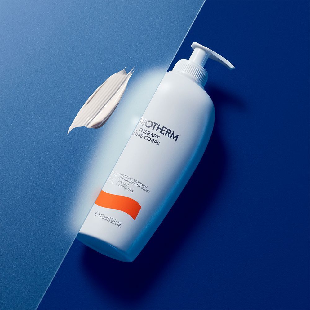 Weiße Flasche mit Pumpverschluss. Aufschrift: BIOTHERM, OIL THERAPY BAUME CORPS. Orangefarbener Streifen. Klecks Creme daneben.