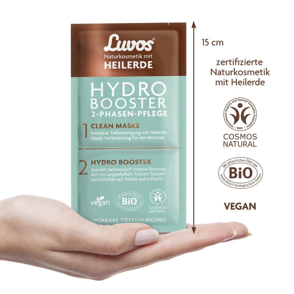Eine Hand hält einen quadratischen Beutel. Aufschrift: Luvos, Hydro Booster, 2-Phasen-Pflege. Vegan-, Bio- und Cosmos Natural-Siegel.
