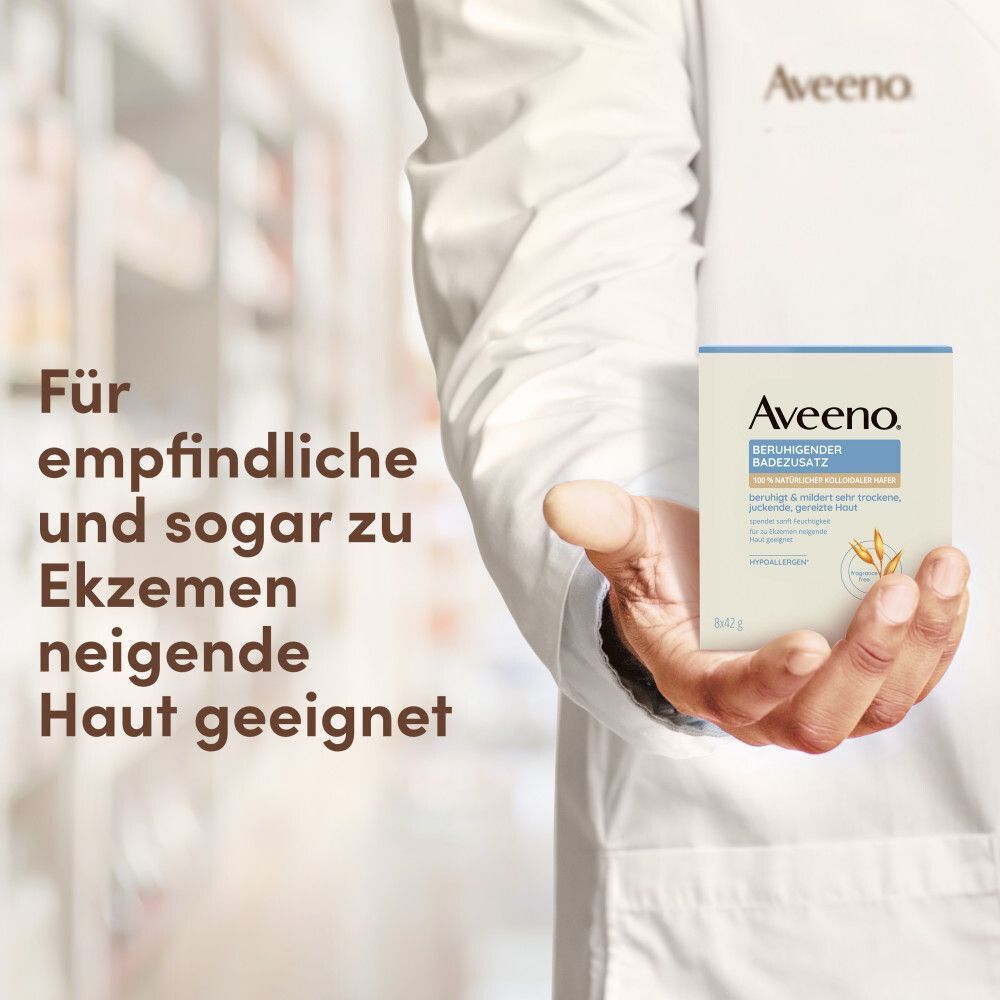 Person hält eine Packung Aveeno® Badezusatz. Text: Für empfindliche und zu Ekzemen neigende Haut geeignet.