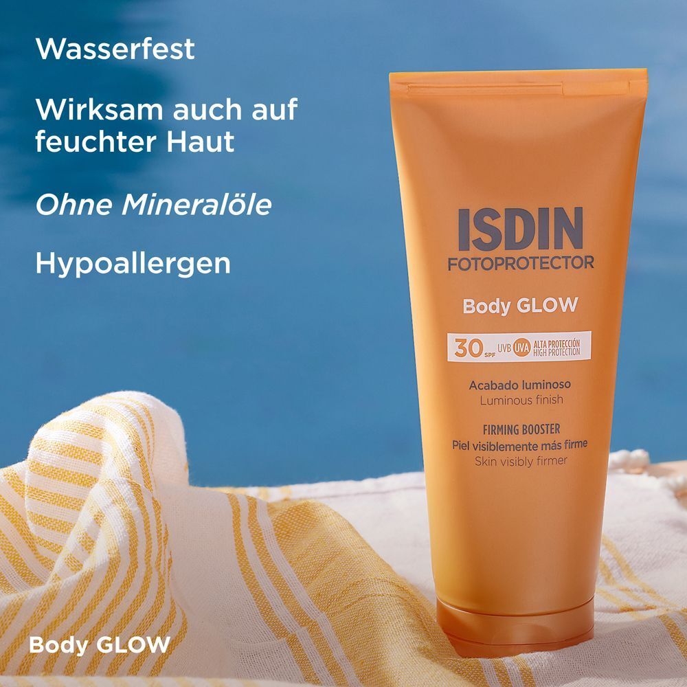 Tube ISDIN Fotoprotector Body Glow liegt neben einem Handtuch. Orangefarbene Tube.