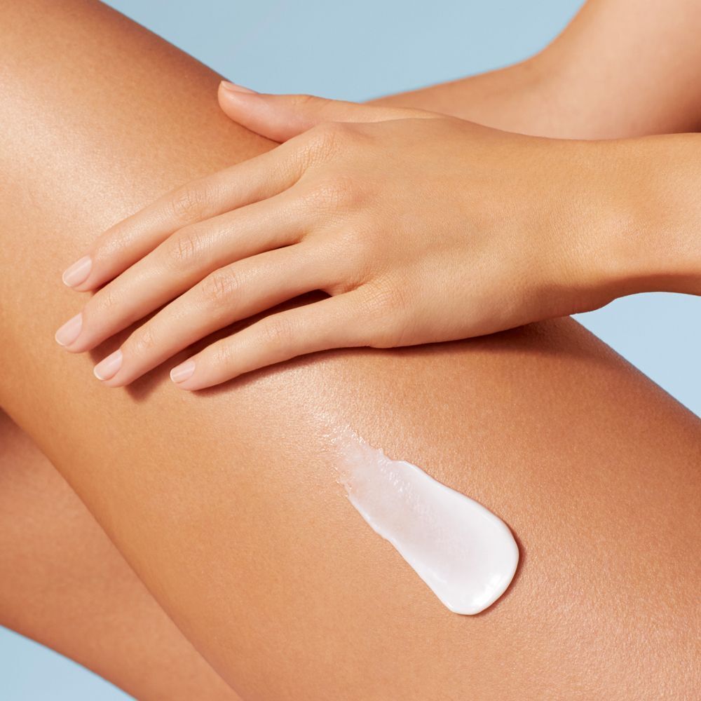 Hand trägt Creme auf Bein auf. Creme-Textur.