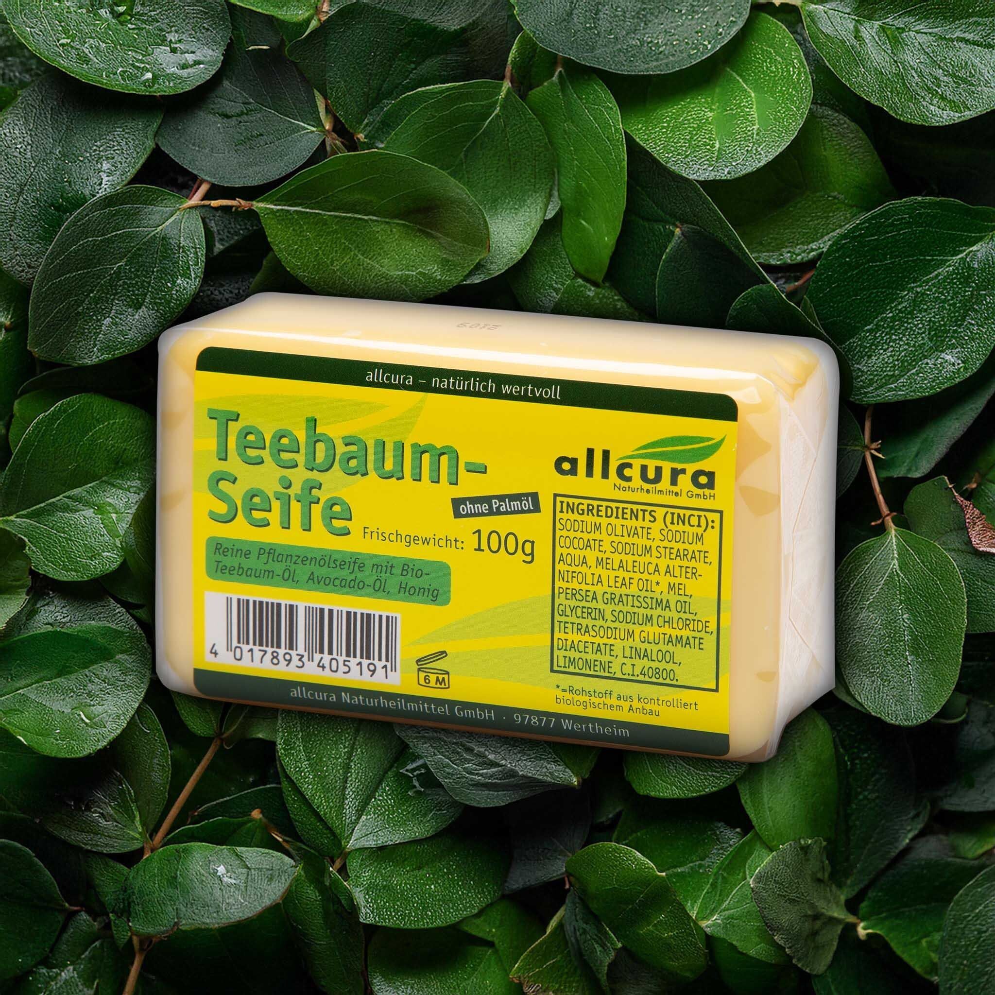 Seifenstück auf Blättern. Gelbes Seifenstück mit grünem Etikett. Aufschrift: Teebaum-Seife, 100g, Inhaltsstoffe.