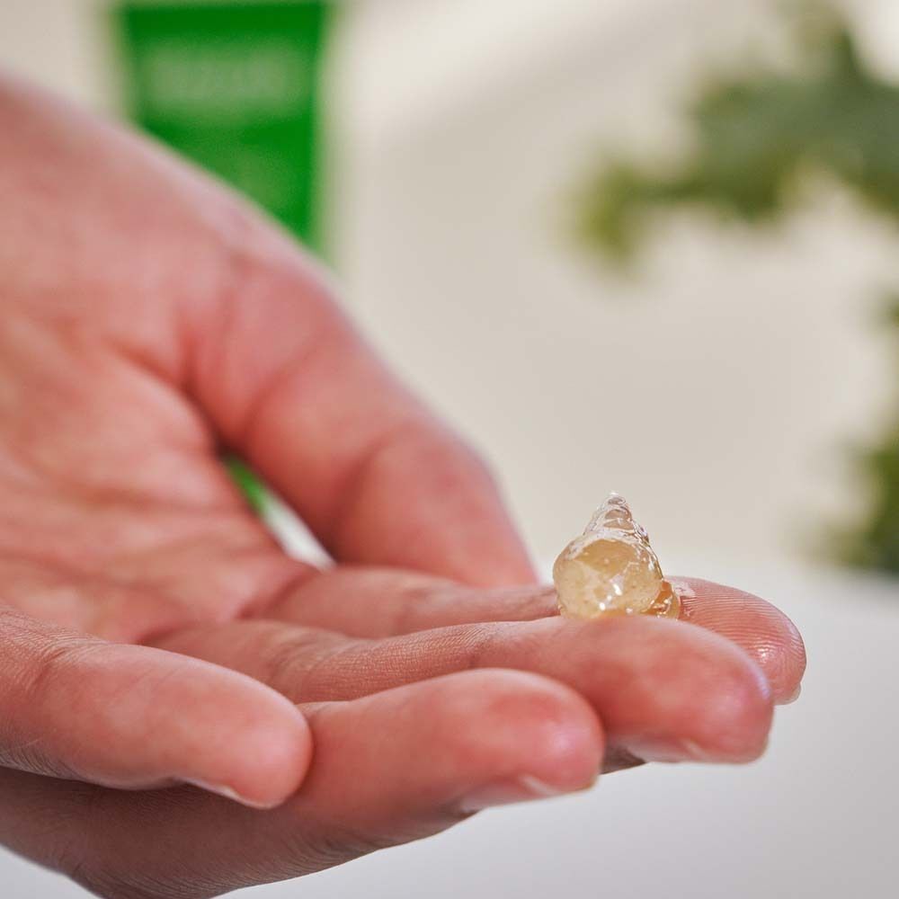 Gelartige Substanz auf der Hand. Farbton: transparent, leicht gelblich. Helle Umgebung.