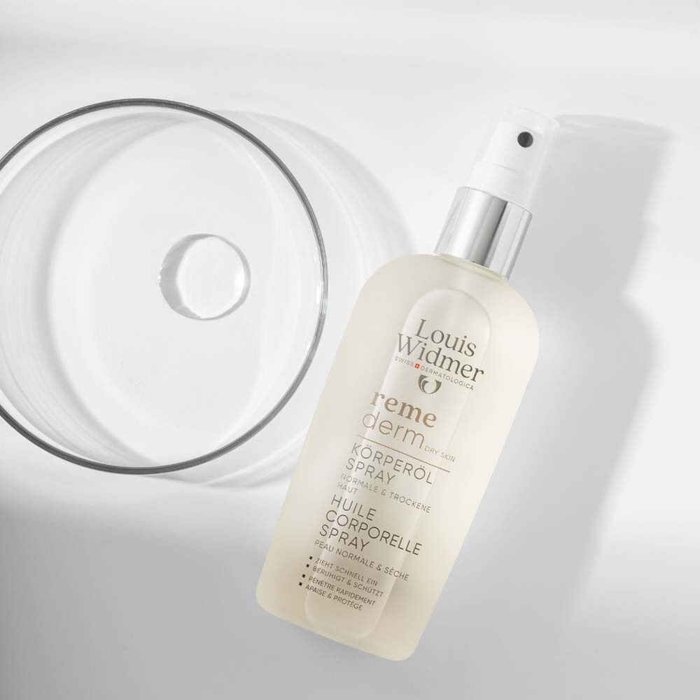 Louis Widmer Remederm Körperöl Spray neben Glasbehälter. Produktbezeichnung und Logo sichtbar.