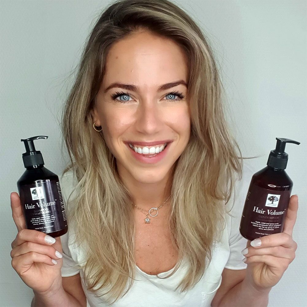 Frau hält zwei Flaschen NEW NORDIC Hair Volume™ Conditioner. Braune Flaschen mit schwarzem Pumpverschluss.