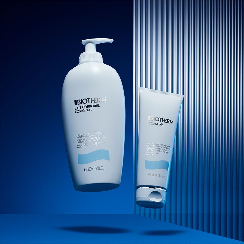 BIOTHERM Lait Corporel Original und BIOTHERM Biomains Handcreme auf blauem Hintergrund. Aufschrift: Biomains, Lait Corporel.
