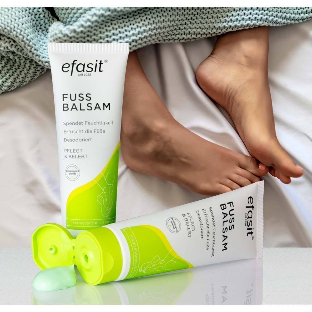Zwei Tuben efasit® FUSS BALSAM und Füße auf Bettwäsche. Eine Tube geöffnet, Produkt sichtbar. Text: FUSS BALSAM.