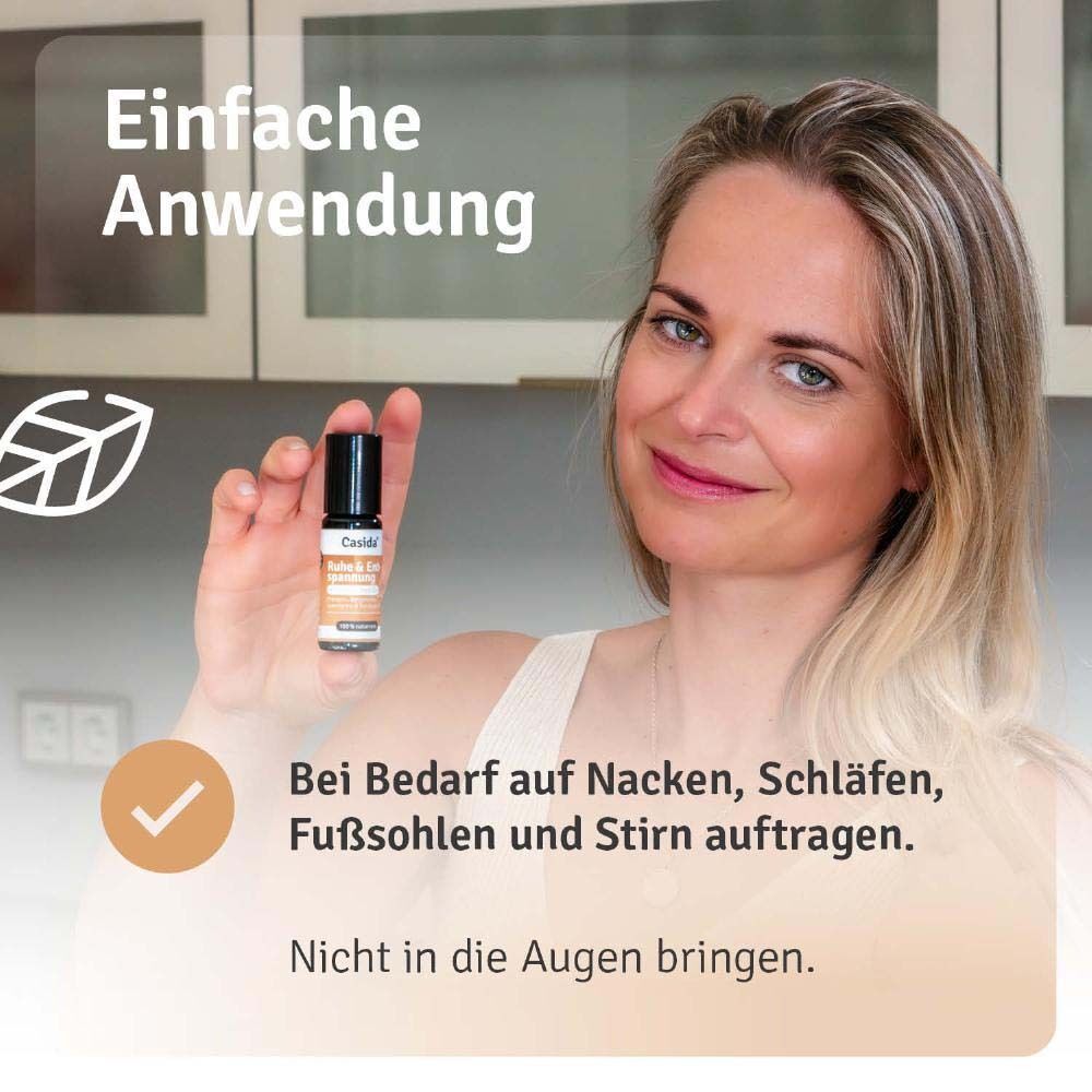 Frau hält Roll-On-Flasche. Aufschrift: Casida, Ruhe & Entspannung. Anwendung: Nacken, Schläfen, Fußsohlen, Stirn. Nicht in die Augen bringen.