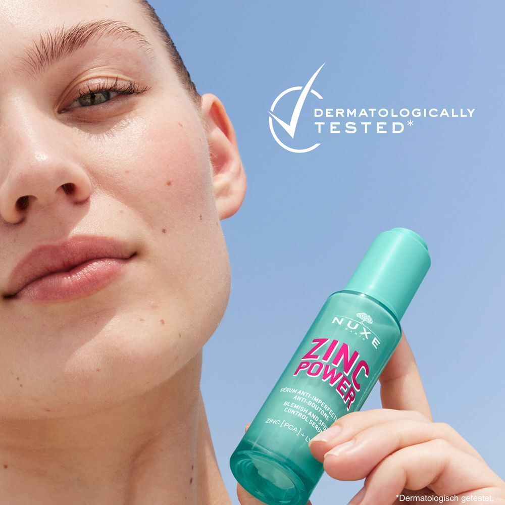 Frau hält eine Flasche NUXE Zinc Power Serum. Aufschrift: ZINC POWER, Serum gegen Hautunreinheiten. Dermatologisch getestet.