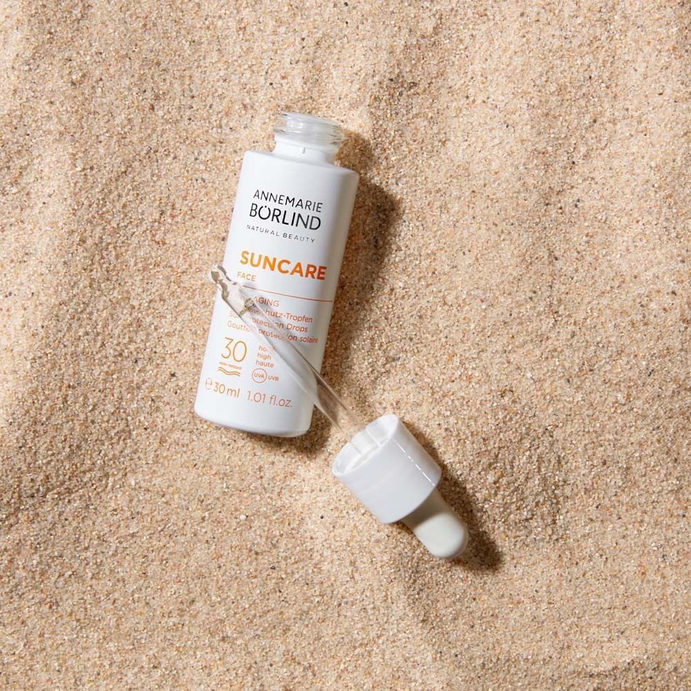 Weiße Flasche mit Tropfaufsatz auf Sand. Aufschrift: Suncare Face, LSF 30. Marke: Annemarie Börlind.