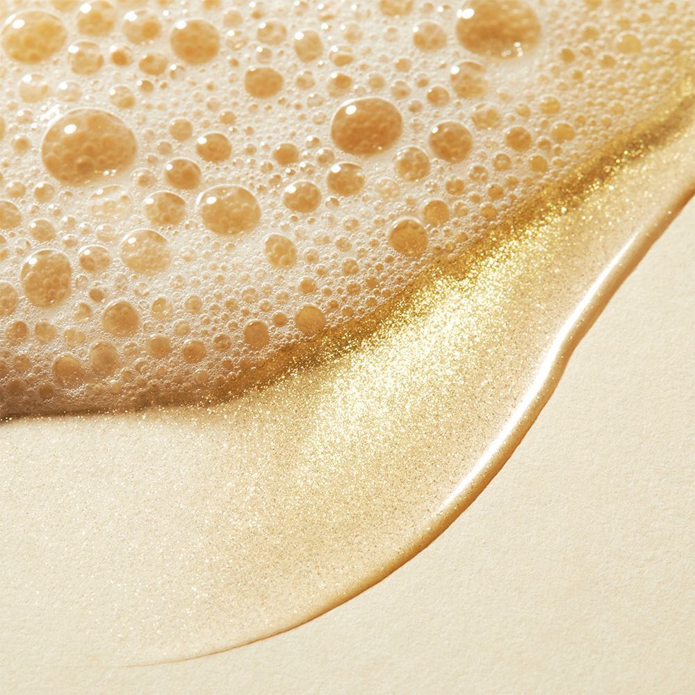 Nahaufnahme von Schaum und Flüssigkeit. Goldfarben, Textur mit Blasen. Flüssigkeit mit Glanz.