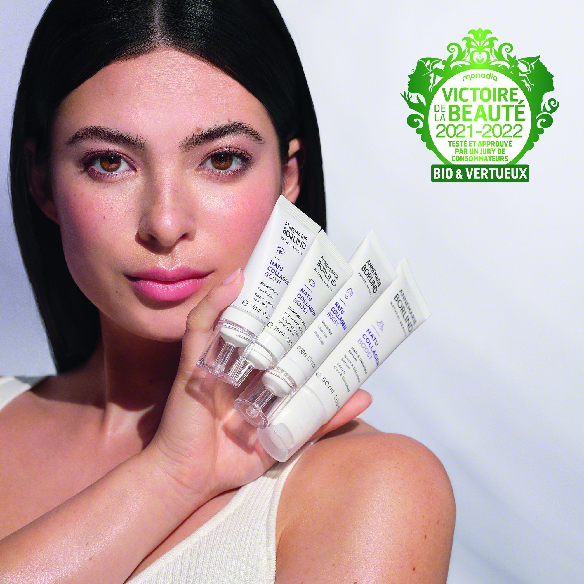 Eine Frau hält vier Tuben ANNEMARIE BÖRLIND NATU COLLAGEN BOOST Gesichtsfluid.