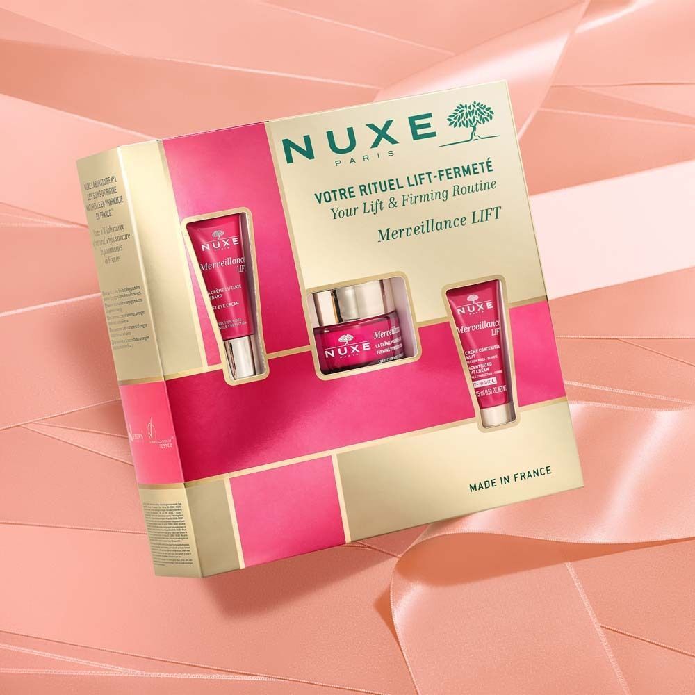 Geschenkset mit Kosmetikprodukten. Goldfarbene Verpackung mit rosa Akzenten. Enthält Tuben und Tiegel. NUXE-Logo.