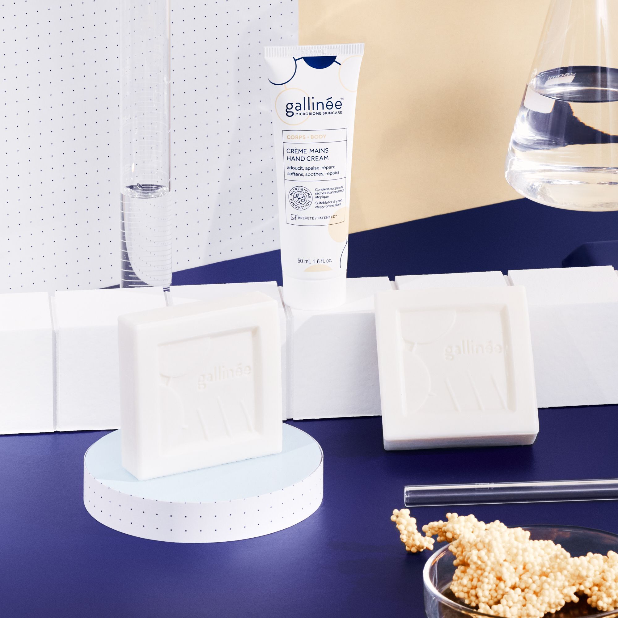 Zwei Seifenstücke und eine Handcreme. Die Seifen sind quadratisch und cremefarben. Die Creme ist in einer Tube.