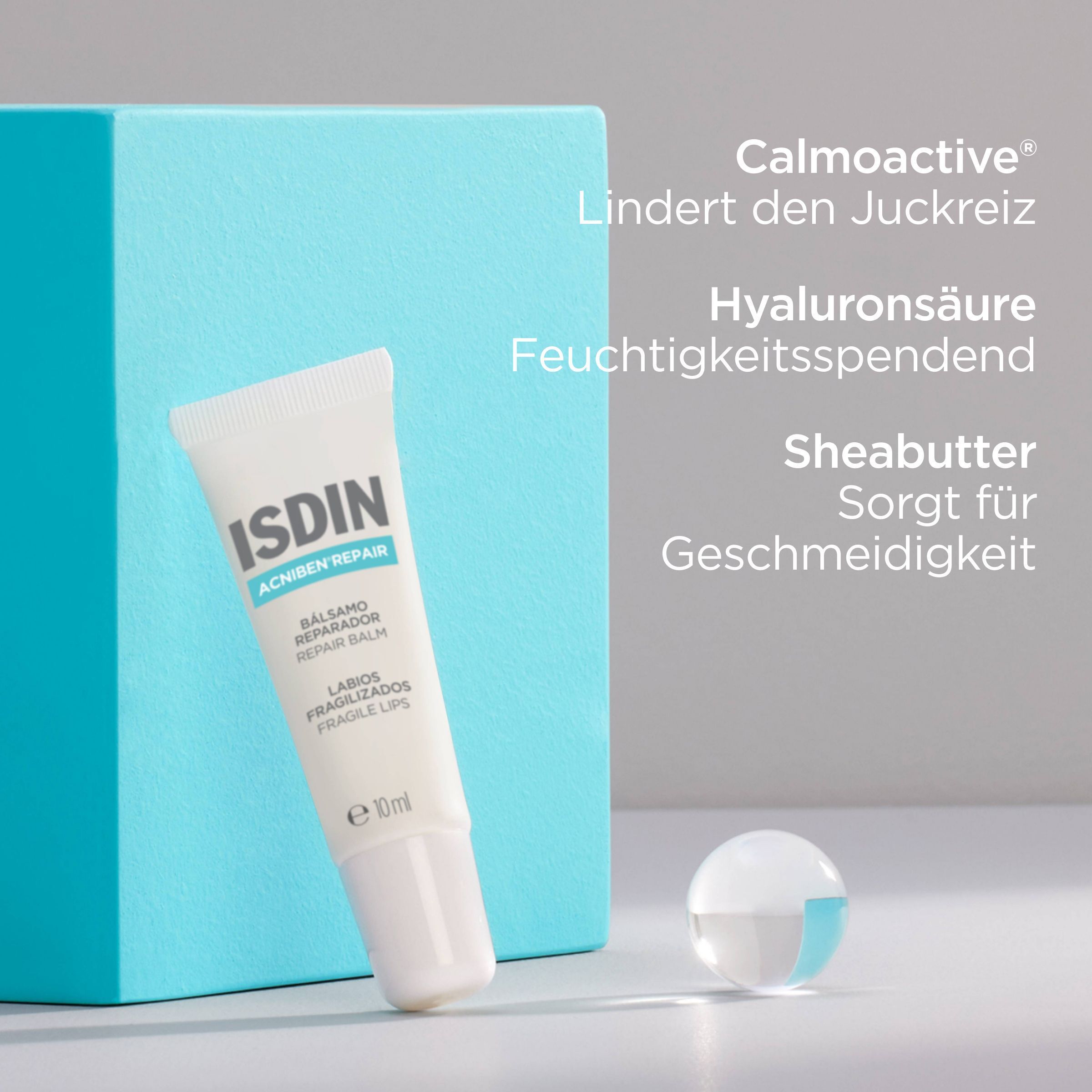 ISDIN Acniben Repair Lippenbalsam-Tube. Text: Calmoactive, Hyaluronsäure, Sheabutter. Blaue Box und Kugel.
