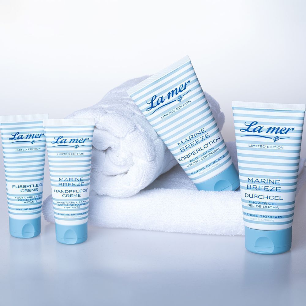 Verschiedene Produkte auf einem weißen Handtuch. Produkte: Fußpflegecreme, Handpflegecreme, Körperlotion, Duschgel. Design: blau-weiß gestreift. Aufschrift: La mer.