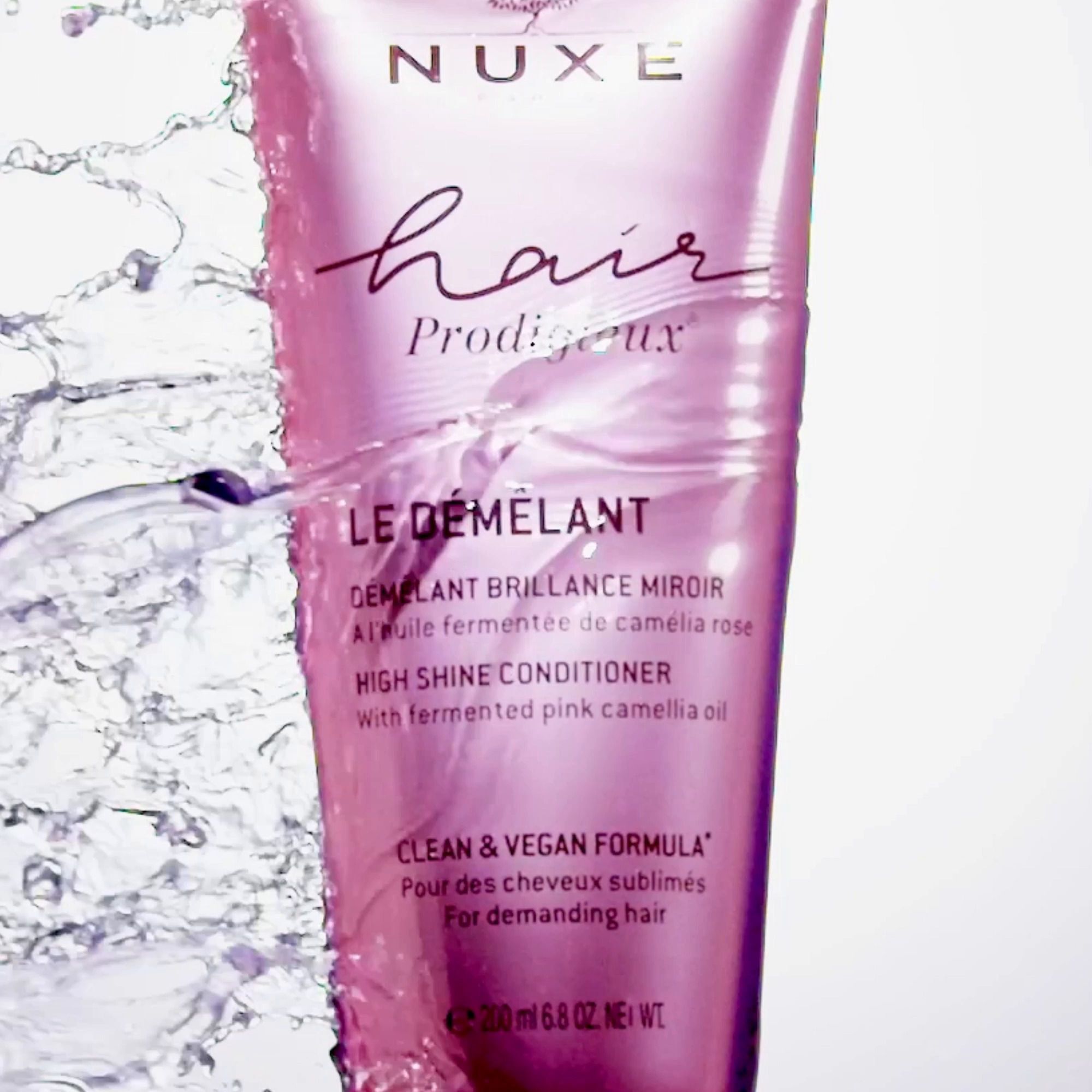 Rosa Tube mit Produktnamen und Wasser spritzt. Aufschrift: NUXE, Hair Prodigieux, Le Démêlant, High Shine Conditioner.