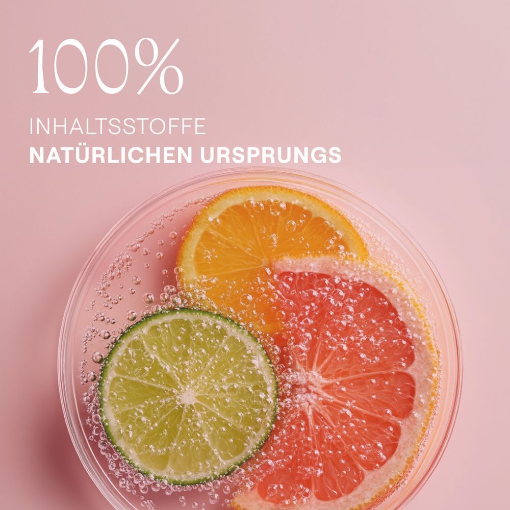 Zitrusfrüchte in einer Glasschale. Text: 100% Inhaltsstoffe natürlichen Ursprungs. Rosa Hintergrund.