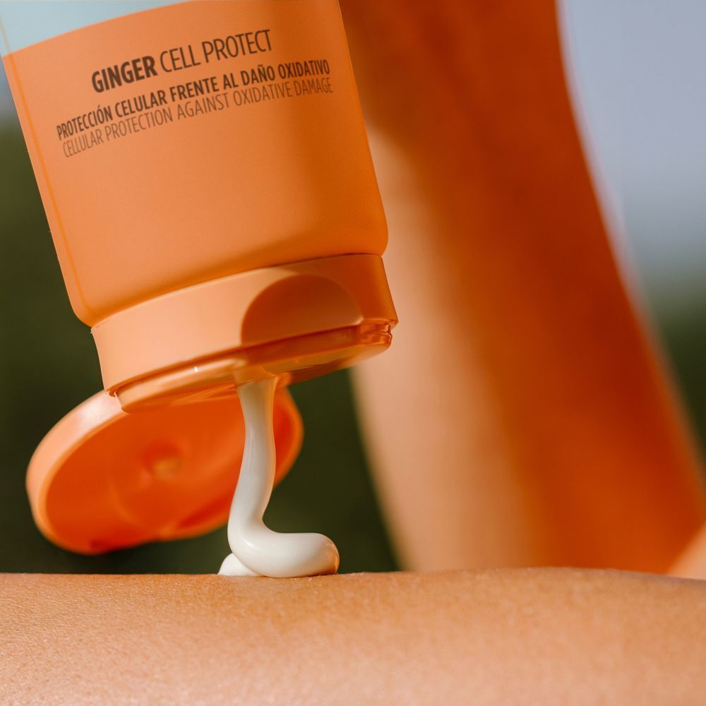 Sonnencreme wird aus einer Tube auf die Haut aufgetragen. Orangefarbene Tube mit Text. Weißes Produkt kommt heraus.