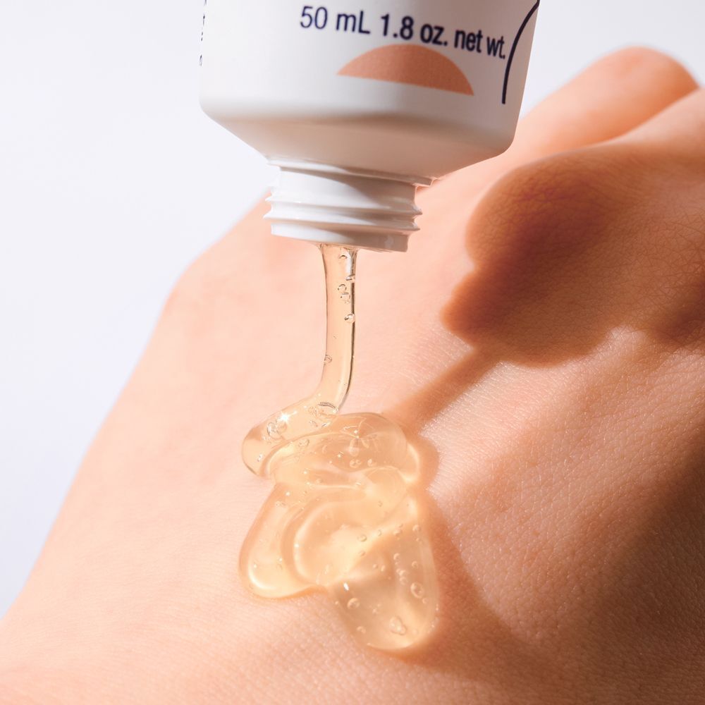 Hand, die eine transparente, gelartige Substanz aus einer Tube empfängt. Die Substanz tropft auf die Haut.