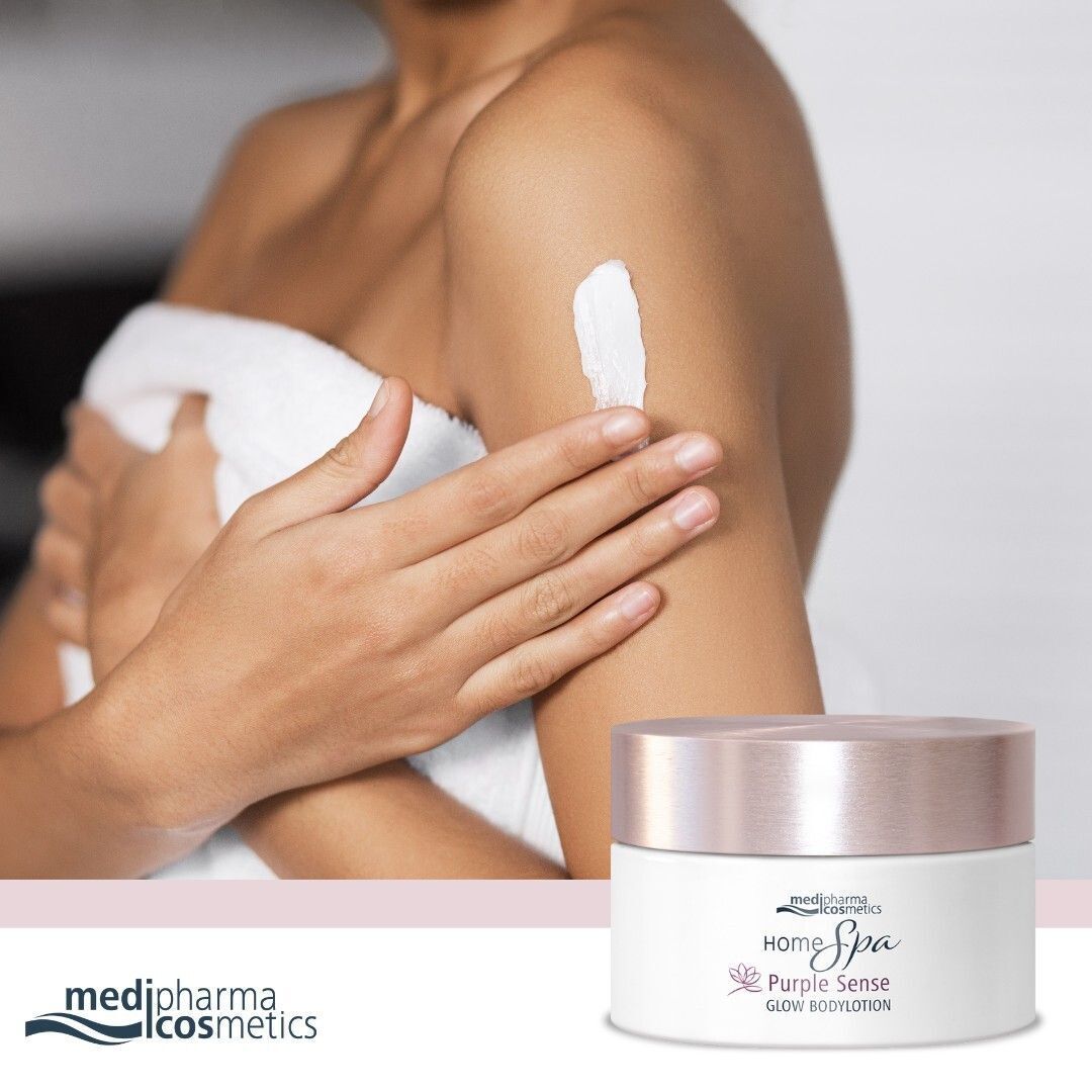 Eine Frau trägt Bodylotion auf ihren Arm auf. Daneben ein weißer Tiegel mit rosafarbenem Deckel.