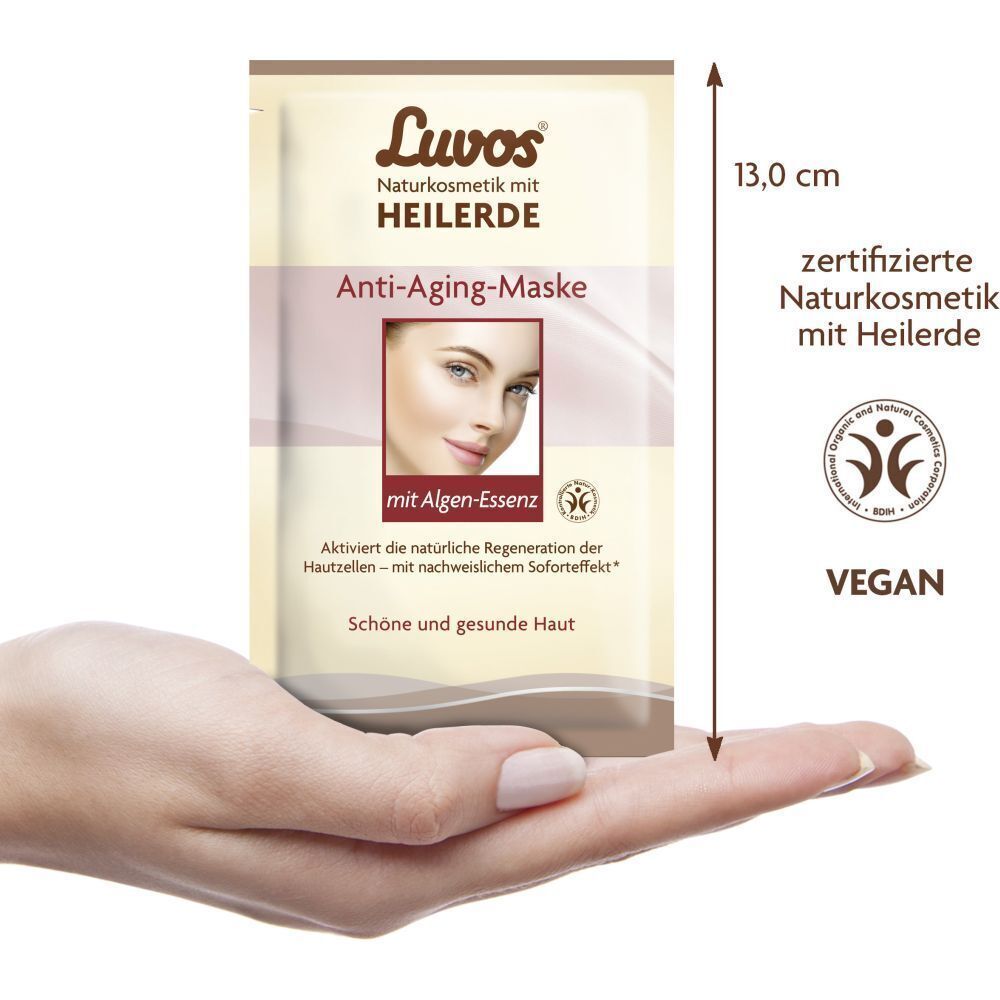 Ein Beutel Luvos Anti-Aging-Maske, gehalten in einer Hand. Maße: 13,0 cm. Aufdruck: „Zertifizierte Naturkosmetik mit Heilerde“.