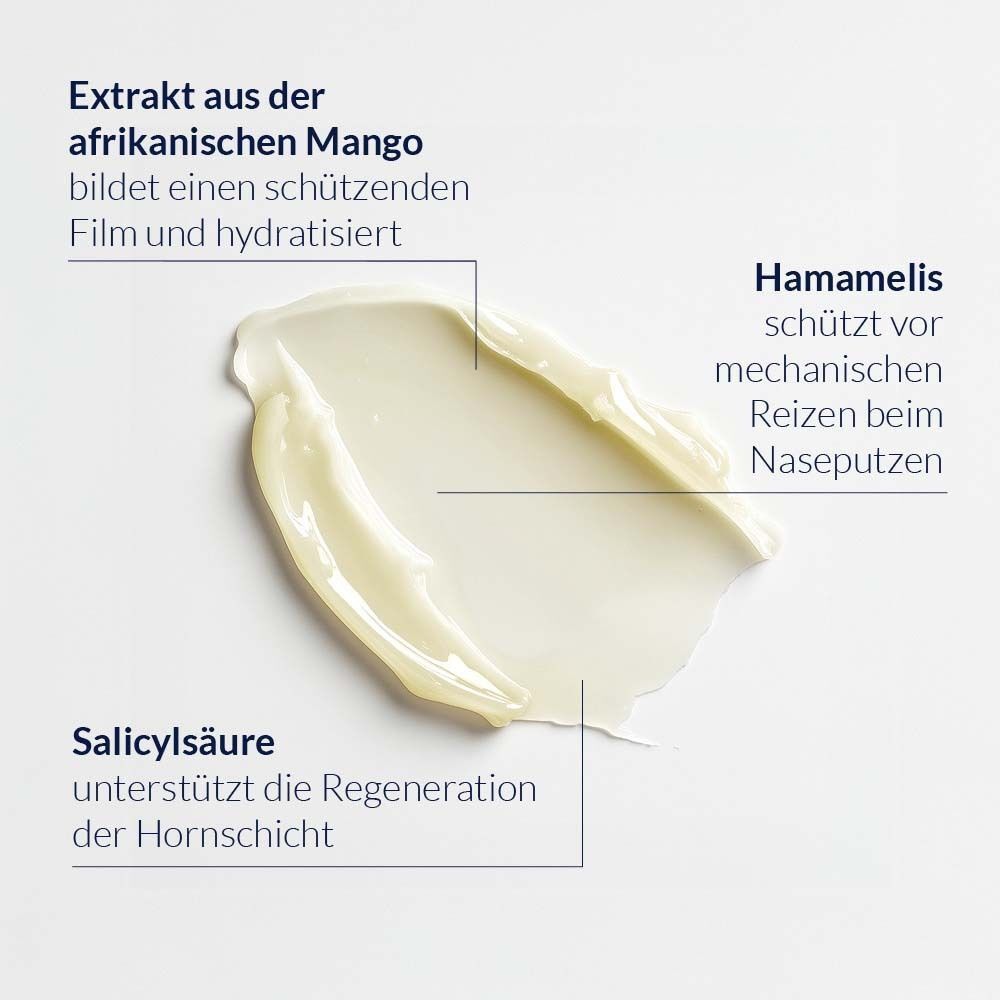 Nahaufnahme einer Creme. Text: Extrakt aus Mango, Hamamelis, Salicylsäure. Creme-Textur auf hellem Hintergrund.