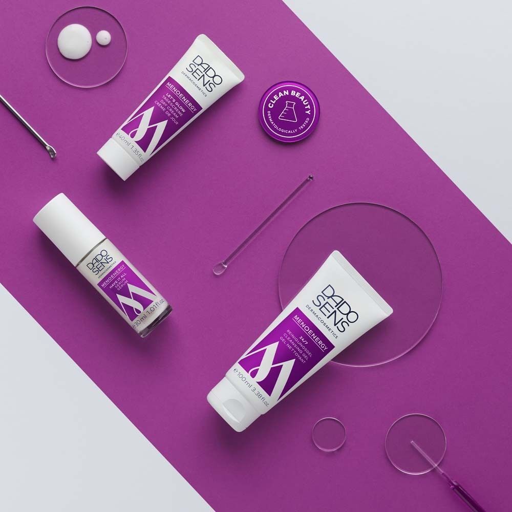 Verschiedene DADO SENS Produkte auf lila Hintergrund. Serum, Creme, Reiniger. Text: Menoenergy.