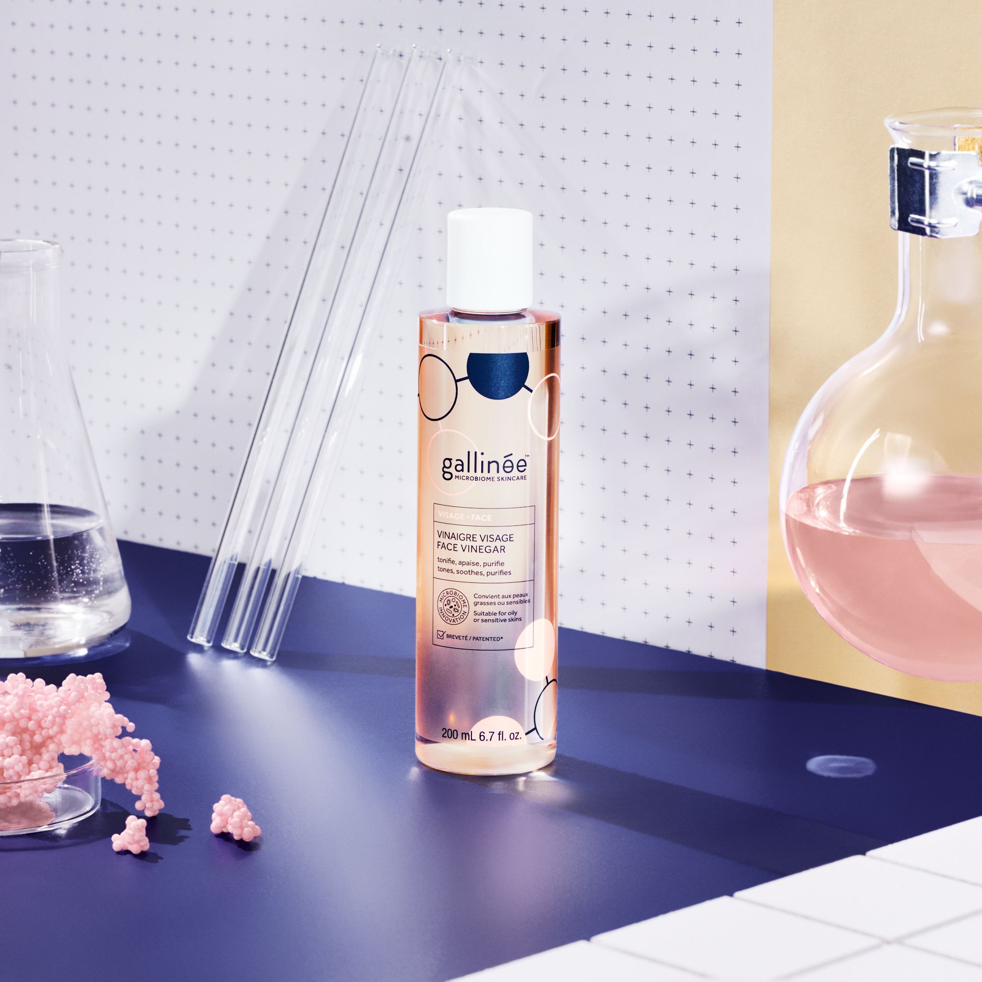 Flasche mit weißem Deckel. Aufschrift: Vinaigre Visage Face Vinegar. 200 ml. Labor-Hintergrund mit Reagenzgläsern.